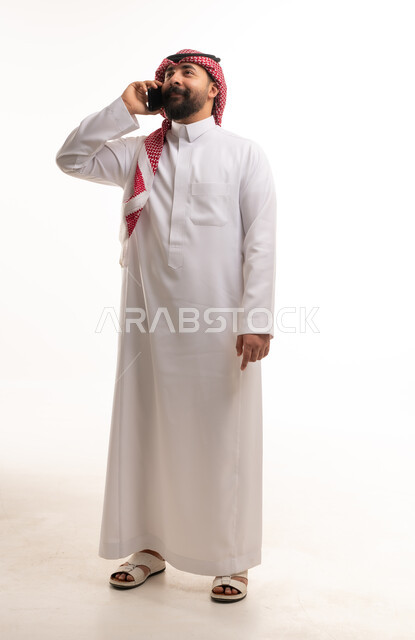 رجل سعودي بالثوب التقليدي يتحدث بالجوال