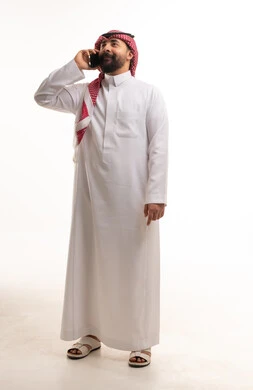 Saudi Man in Traditional Thobe Talking on Smartphone