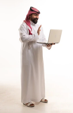 رجل سعودي بالزي التقليدي يستخدم اللابتوب
