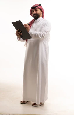 رجل سعودي يرتدي الثوب التقليدي ويكتب على ملف في الاستوديو
