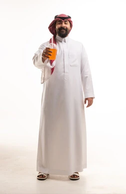 رجل سعودي بالزي التقليدي يحمل عصير برتقال