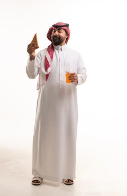 رجل سعودي بالزي التقليدي مع سمبوسة وعصير