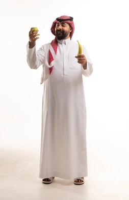 رجل سعودي بالزي التقليدي يحمل فواكه طازجة