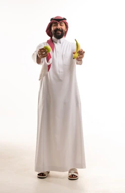 رجل سعودي بالزي التقليدي يحمل الفواكه