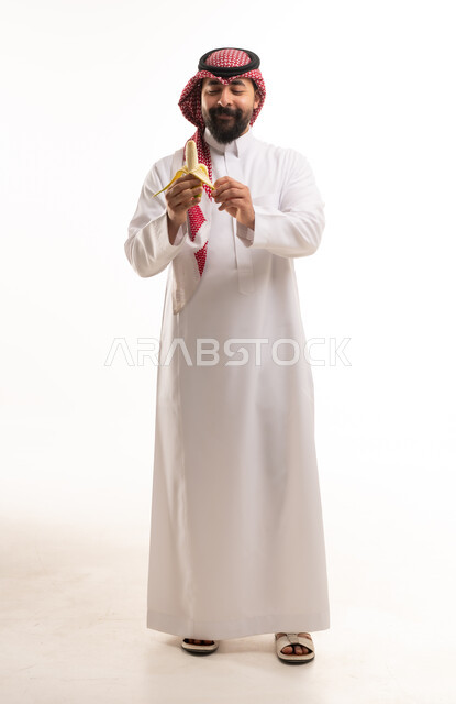 رجل سعودي بالزي التقليدي يقشر موزة