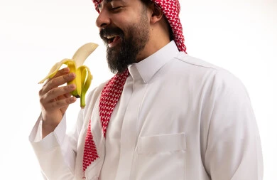 رجل سعودي بالثوب التقليدي يأكل الموز