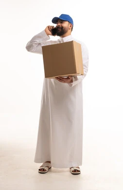 رجل توصيل سعودي يحمل طرد ويتحدث بالهاتف