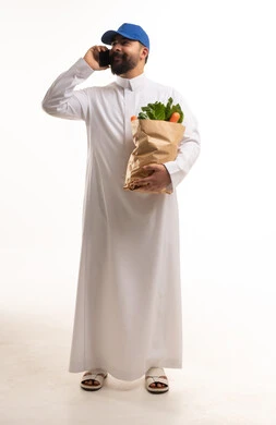 Saudi Man in Thobe Holding Grocery Bag Talking on Phone