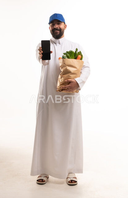 رجل سعودي يحمل حقيبة بقالة وتطبيق هاتف ذكي