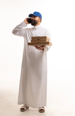رجل سعودي بالثوب يحمل علب بيتزا ويتحدث بالهاتف