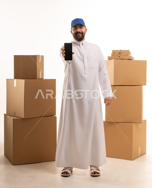 مندوب توصيل سعودي يحمل هاتف ذكي مع صناديق شحن