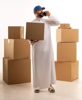 مندوب توصيل سعودي مع صناديق كرتونية يتحدث بالهاتف