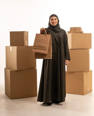امرأة سعودية مع حقائب تسوق وصناديق توصيل