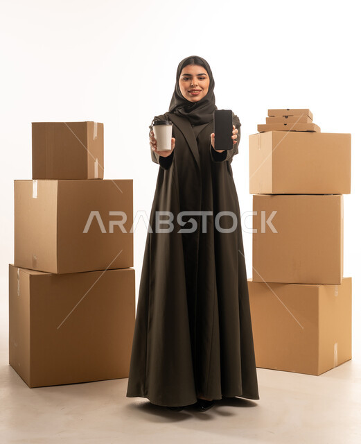 امرأة سعودية مع هاتف ذكي وصناديق شحن