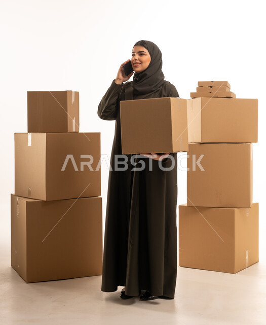 امرأة سعودية مع صناديق شحن تتحدث بالهاتف