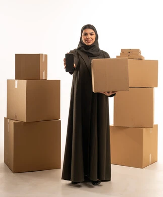امرأة سعودية تحمل هاتفاً وصناديق شحن وتوصيل