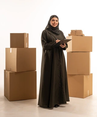 امرأة سعودية تحمل ملف ملاحظات مع صناديق كرتونية