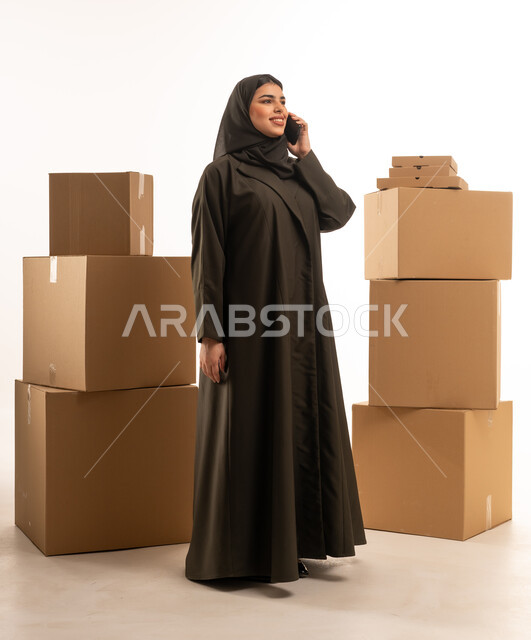 امرأة سعودية مع صناديق شحن تتحدث بالهاتف