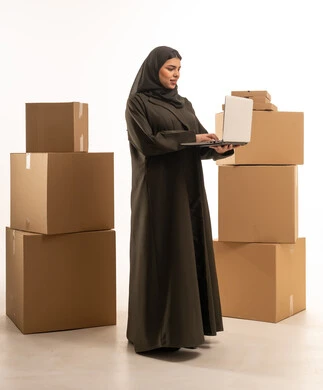سيدة أعمال سعودية تستخدم الكمبيوتر مع صناديق شحن