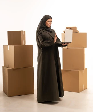 امرأة سعودية مع كمبيوتر محمول وصناديق شحن