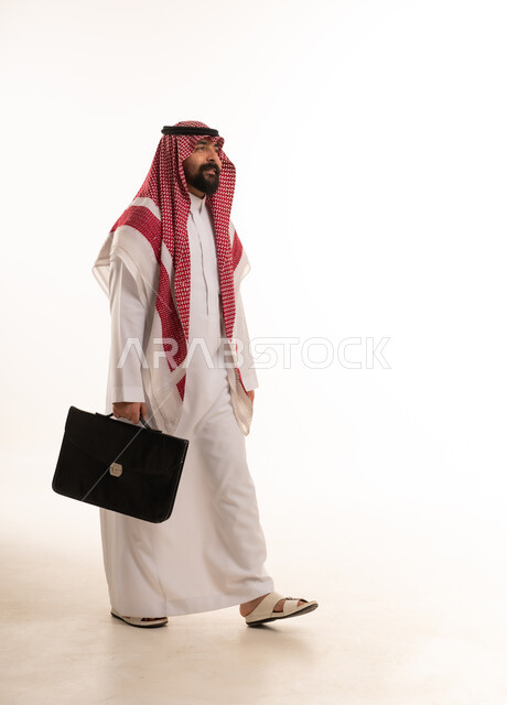 رجل أعمال سعودي يمشي مع حقيبة في الاستوديو