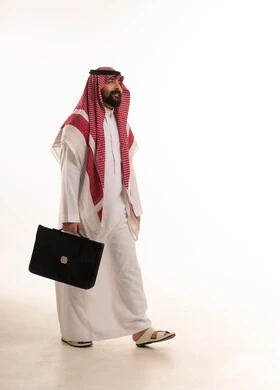 رجل أعمال سعودي يمشي مع حقيبة في الاستوديو