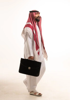 رجل أعمال سعودي يمشي حاملاً حقيبة عمل