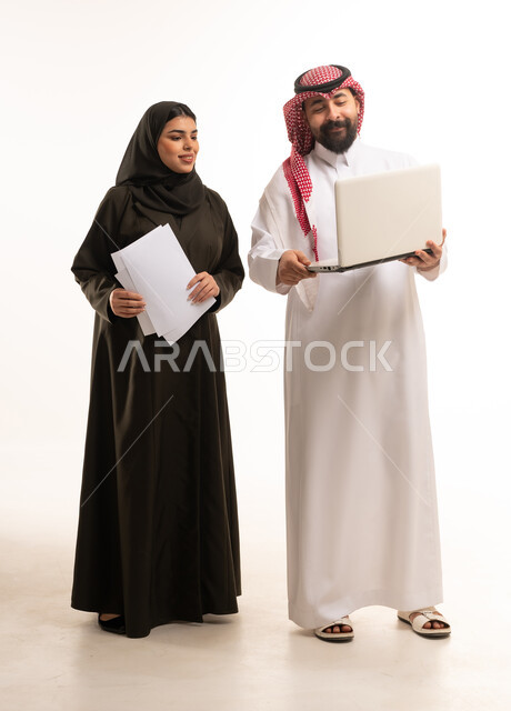 زملاء عمل سعوديون مع كمبيوتر محمول بخلفية بيضاء