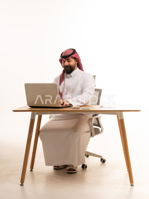 رجل سعودي يعمل على جهاز حاسوب في مكتب مهني