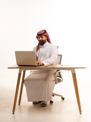 رجل سعودي يعمل على جهاز حاسوب في مكتب مهني