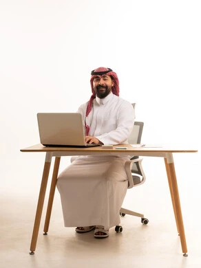 رجل أعمال سعودي على مكتب مع لابتوب