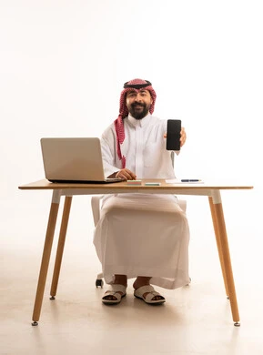 Saudi Businessman at Desk Holding Smartphone Screen