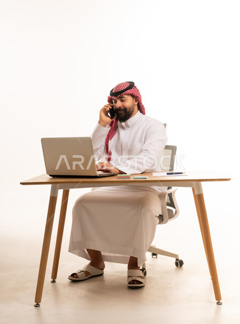 رجل أعمال سعودي يعمل على الكمبيوتر المحمول في المكتب