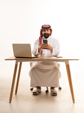 رجل أعمال سعودي يستخدم الهاتف الذكي في المكتب