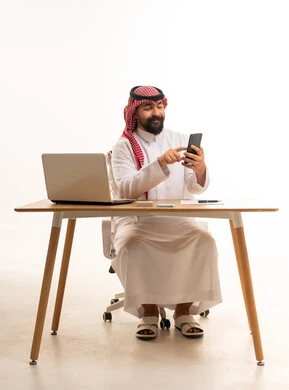 Saudi Businessman Using Smartphone at Office Desk
