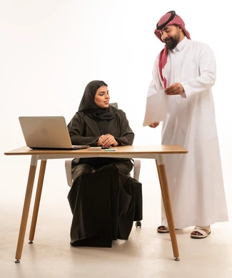 زملاء عمل سعوديون يناقشون وثائق رسمية داخل مكتب عمل