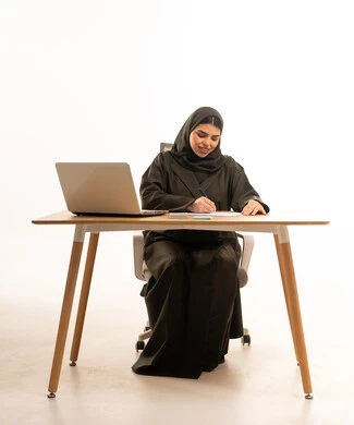 سيدة أعمال إماراتية تكتب على مكتب مع لابتوب