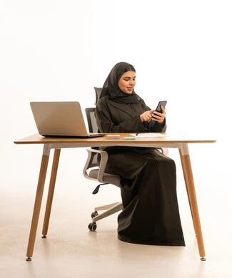 Saudi Businesswoman Using Smartphone at Office Desk