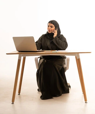 Saudi Businesswoman Working at Desk with Laptop and Phone