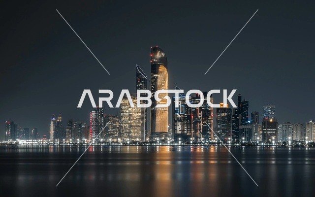 أفق مدينة أبوظبي ليلاً مع انعكاسات ناطحات السحاب