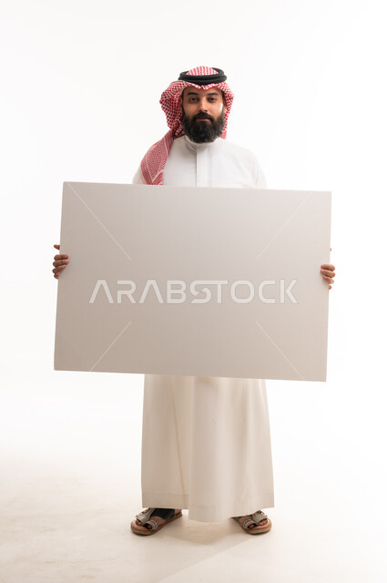 رجل سعودي يحمل لوحة بيضاء فارغة في الاستوديو