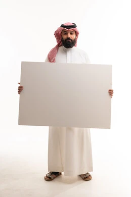 رجل سعودي يحمل لوحة بيضاء فارغة في الاستوديو
