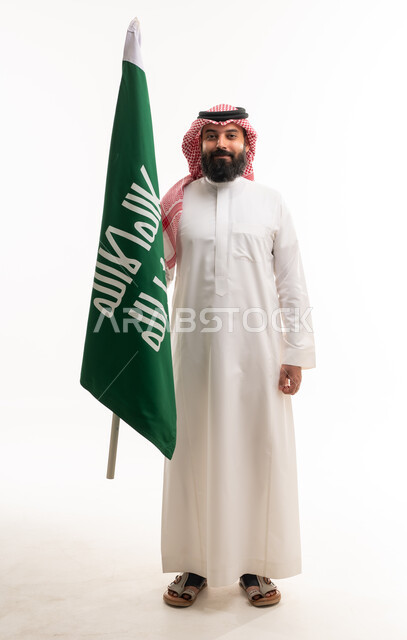 رجل سعودي يمسك بالعلم الوطني على خلفية بيضاء