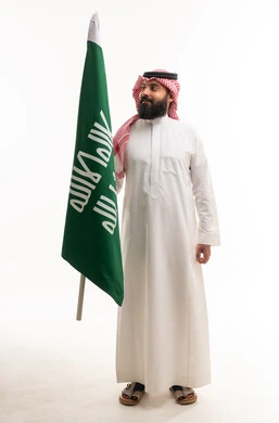 Saudi Man in Traditional Thobe Holding Saudi Flag
