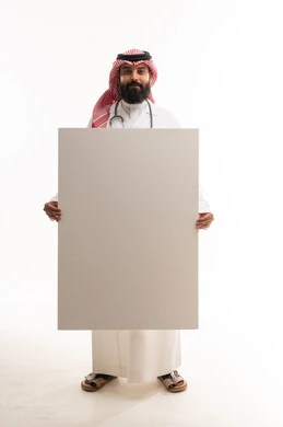 طبيب سعودي يرتدي الثوب التقليدي يحمل لوحة بيضاء فارغة