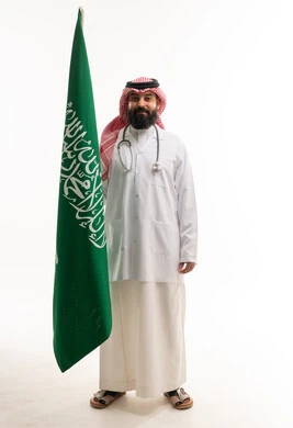 طبيب سعودي يحمل علم المملكة العربية السعودية بخلفية بيضاء