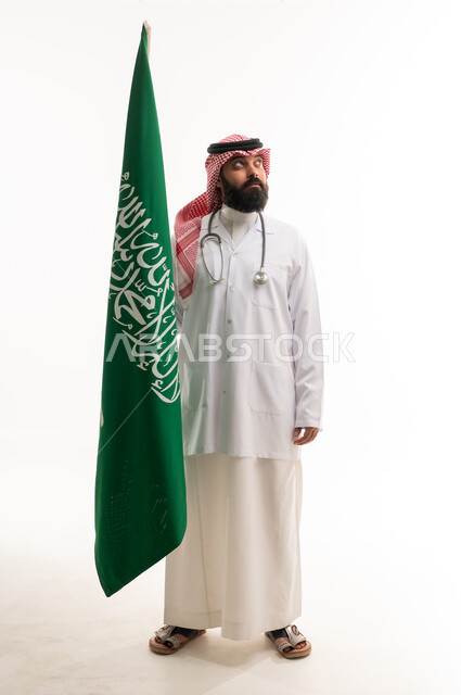 طبيب سعودي يحمل علم المملكة العربية السعودية في استوديو