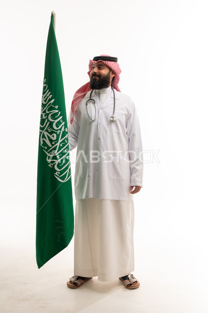 طبيب سعودي بالزي الرسمي مع العلم الوطني
