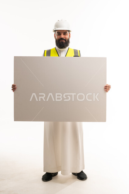 مهندس سعودي يرتدي معدات السلامة يحمل لوحة بيضاء فارغة