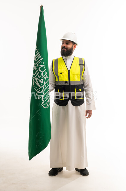 مهندس سعودي يرتدي سترة السلامة ويحمل العلم السعودي